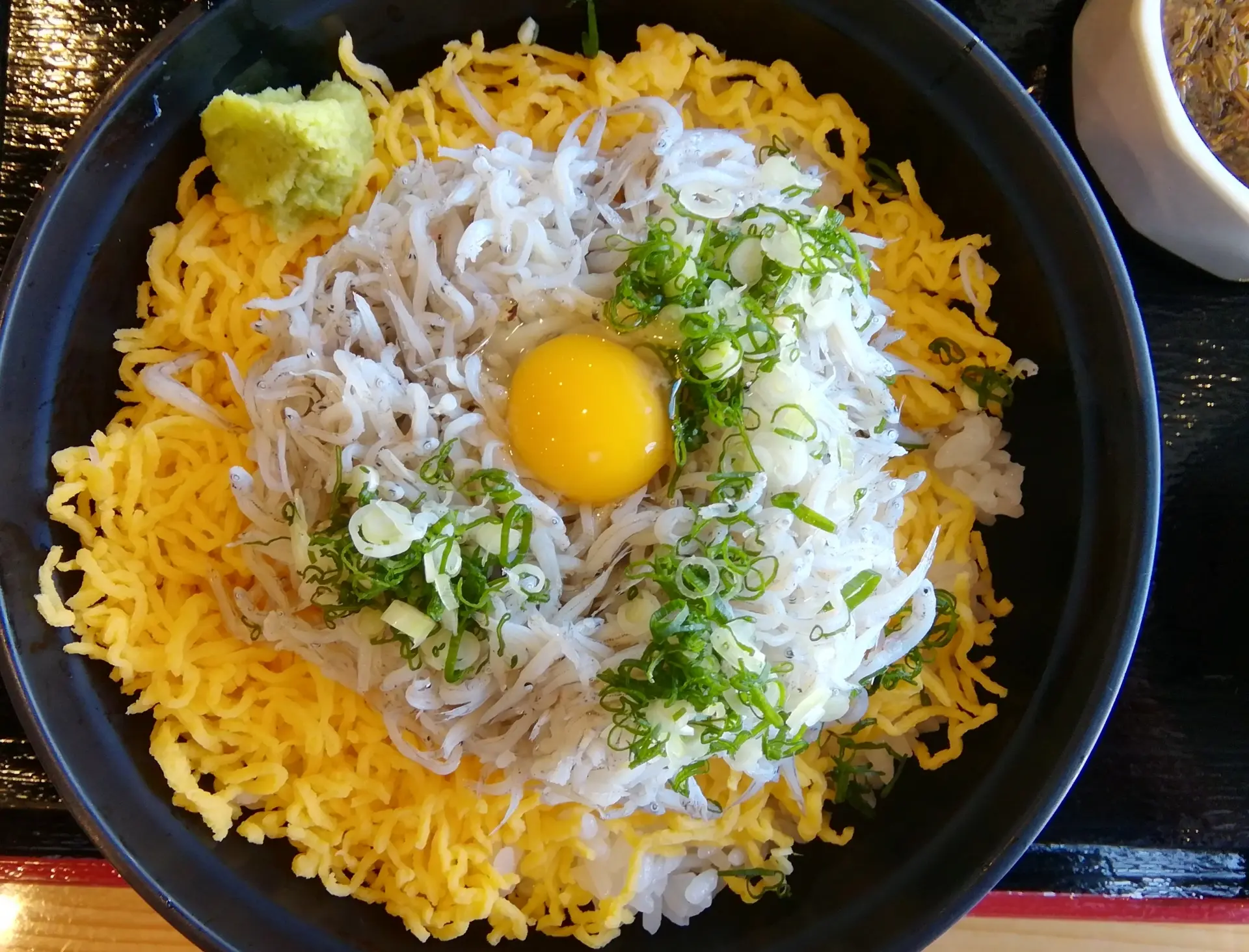 道の駅 北浦街道 豊北のレストランで提供される、彩り豊かなしらす丼。窓の外には青い海と角島大橋の絶景が広がる。